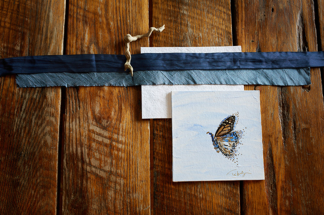 Monarch butterfly wing tatter and painted hind wing featuring acrylic paint and gold leaf on canvas., shown on aged oak background with silk ribbons and driftwood.