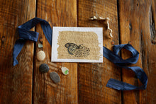 Load image into Gallery viewer, Found butterfly wing (Monarch/ Lepideroptera / Danaus plexippus), ink, acrylic paint, and gold leaf on 5x7 cold press watercolor paper, shown on aged oak background with blue silk ribbon, driftwood, sea glass and pebbles. 
